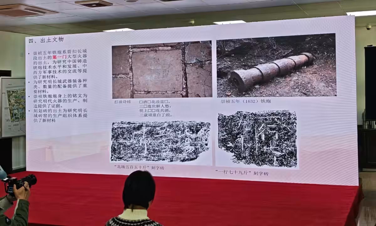 The Image Shows A Large Screen Displaying A Presentation Related To Archaeological Findings At The Great Wall Of China.