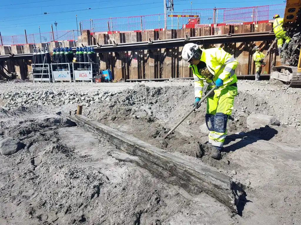 A person in yellow digs up remains of a wreck.