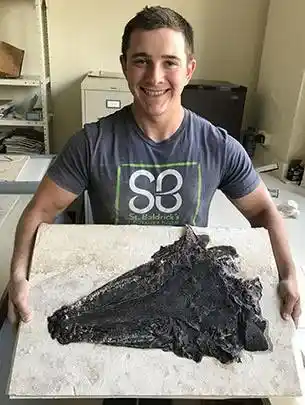 Field Museum preparator Tony Bellos holding the skull after removing the rock that covered it.