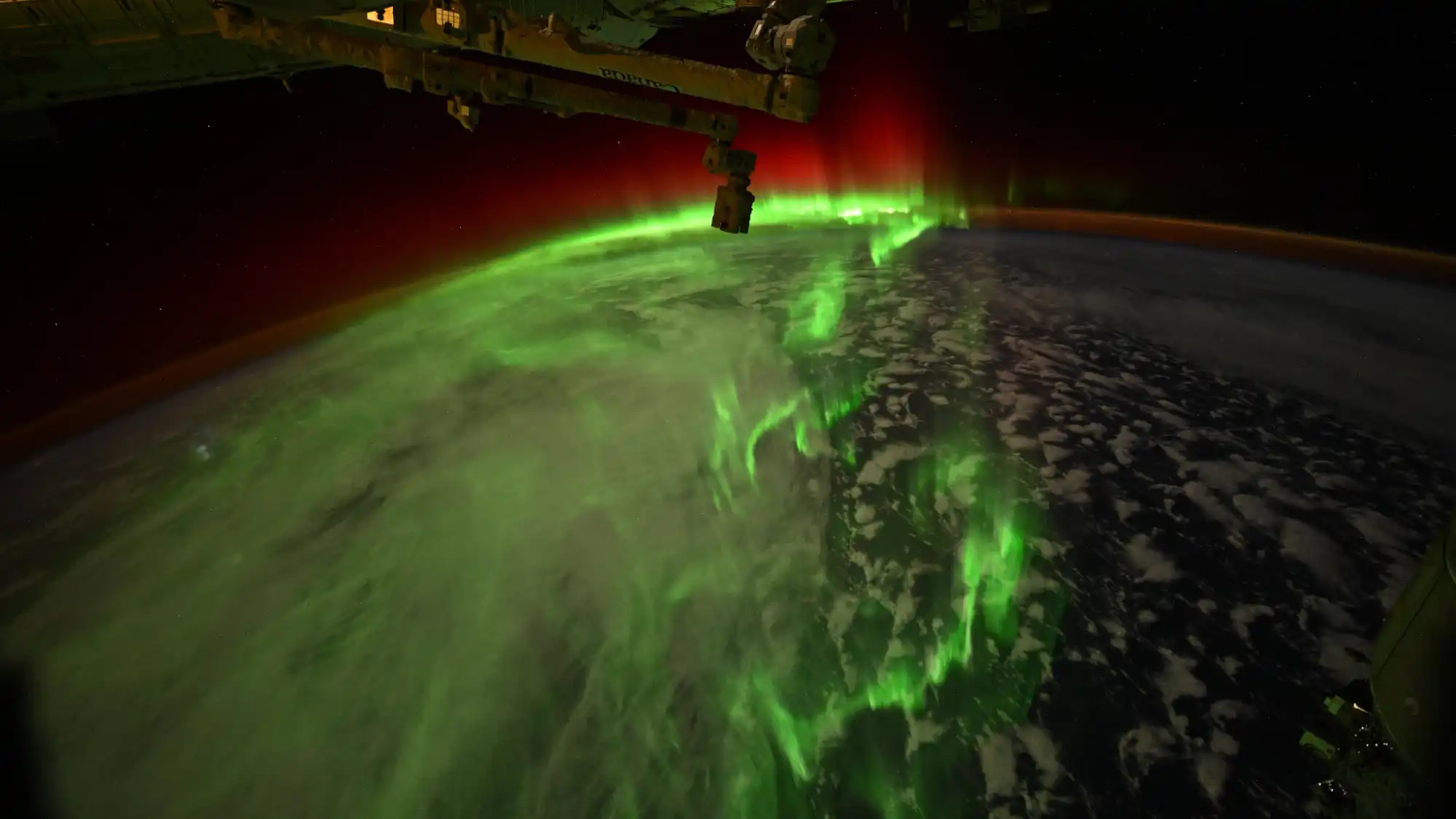 Bright green and red auroras over Earth as seen from space.
