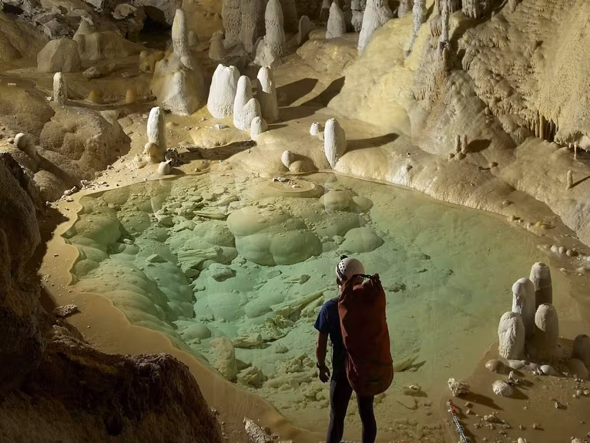 A Cave Explorer Surveys A Mineral Rich Pool Within Lechuguilla Cave, Part Of Carlsbad Caverns National Park.