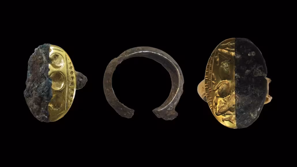 Three ancient rings are seen on a black background. The one in the middle is just the part that goes around the finger, while the other two have flat engraved ovals. Each have a half showing what the rings would have looked like originally.