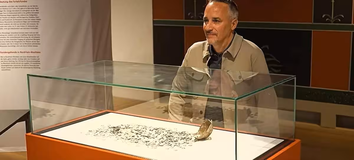 Oliver Riedl Stands Beside A Display Of Ancient Roman Silver Coins Discovered In Germany.