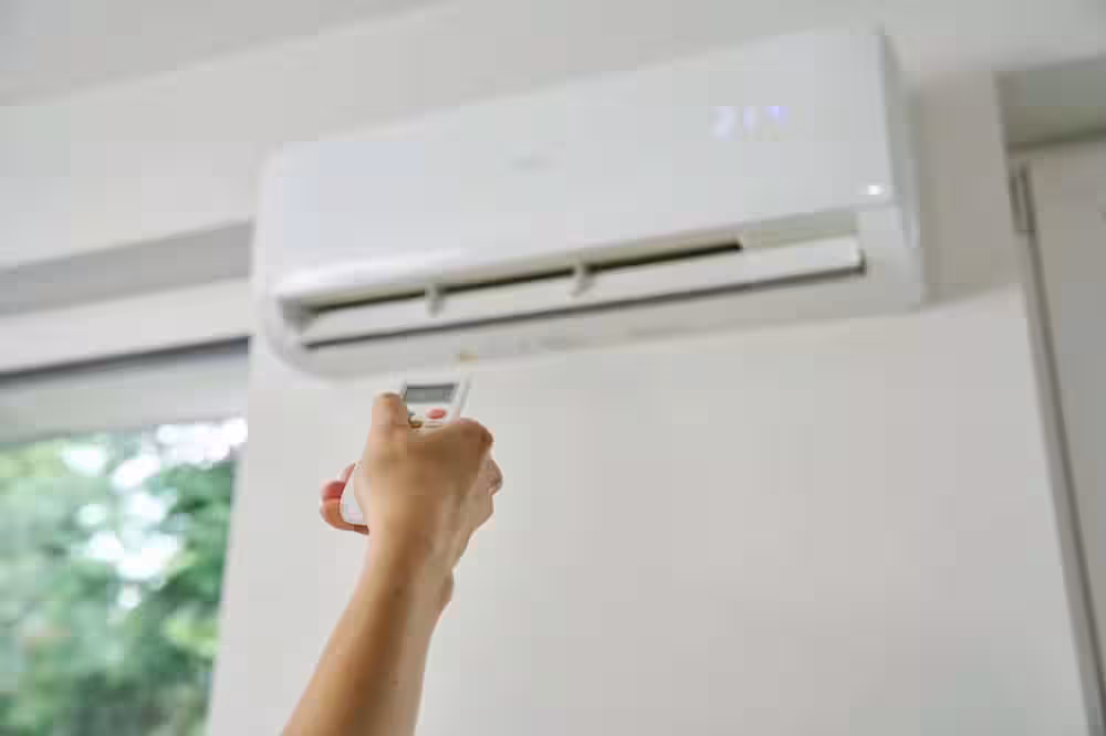 Adjusting,air,conditioner,temperature,with,remote,control.,hand,holds,remote