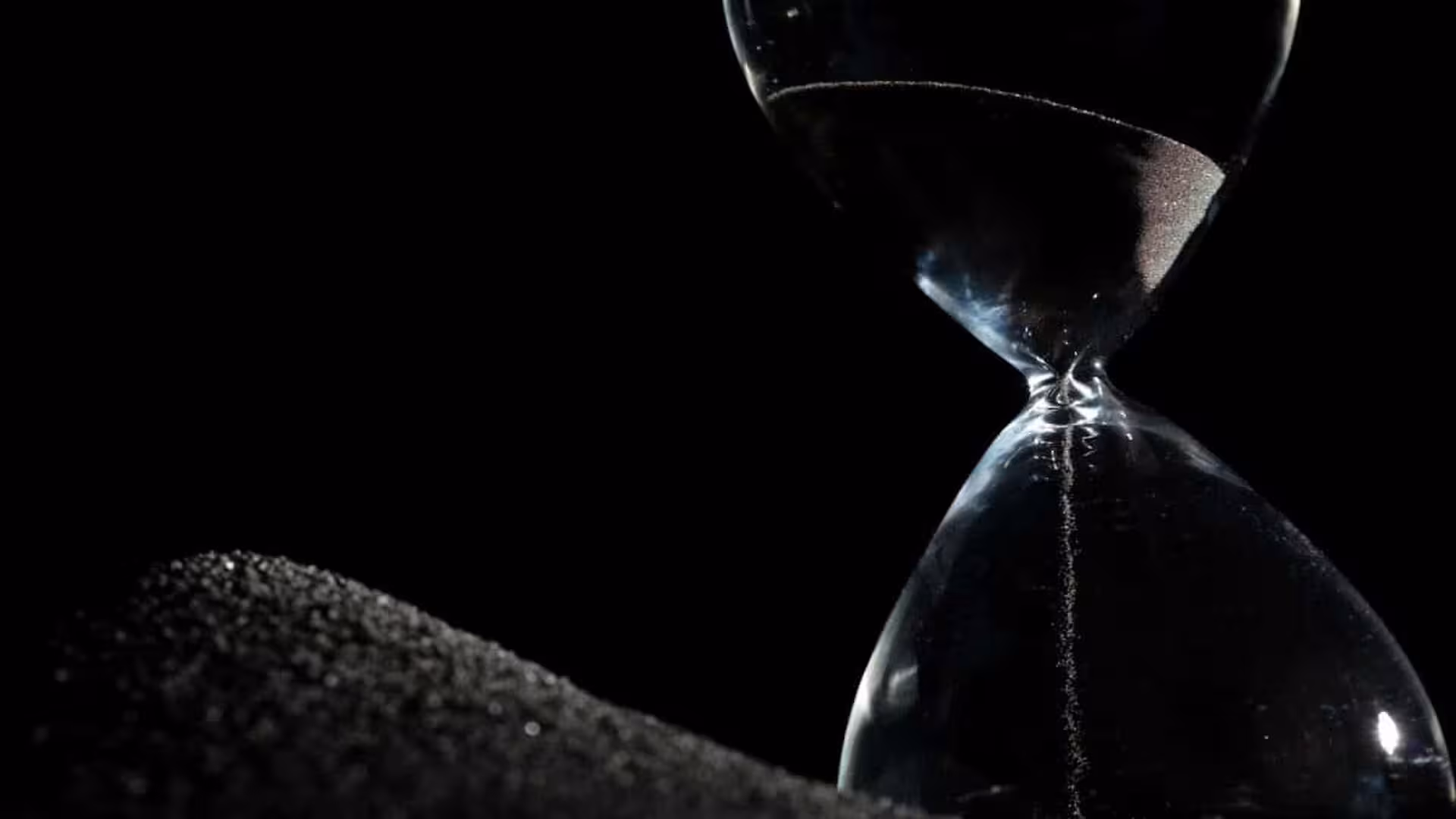 Hourglass Standing On Black Sand Scaled