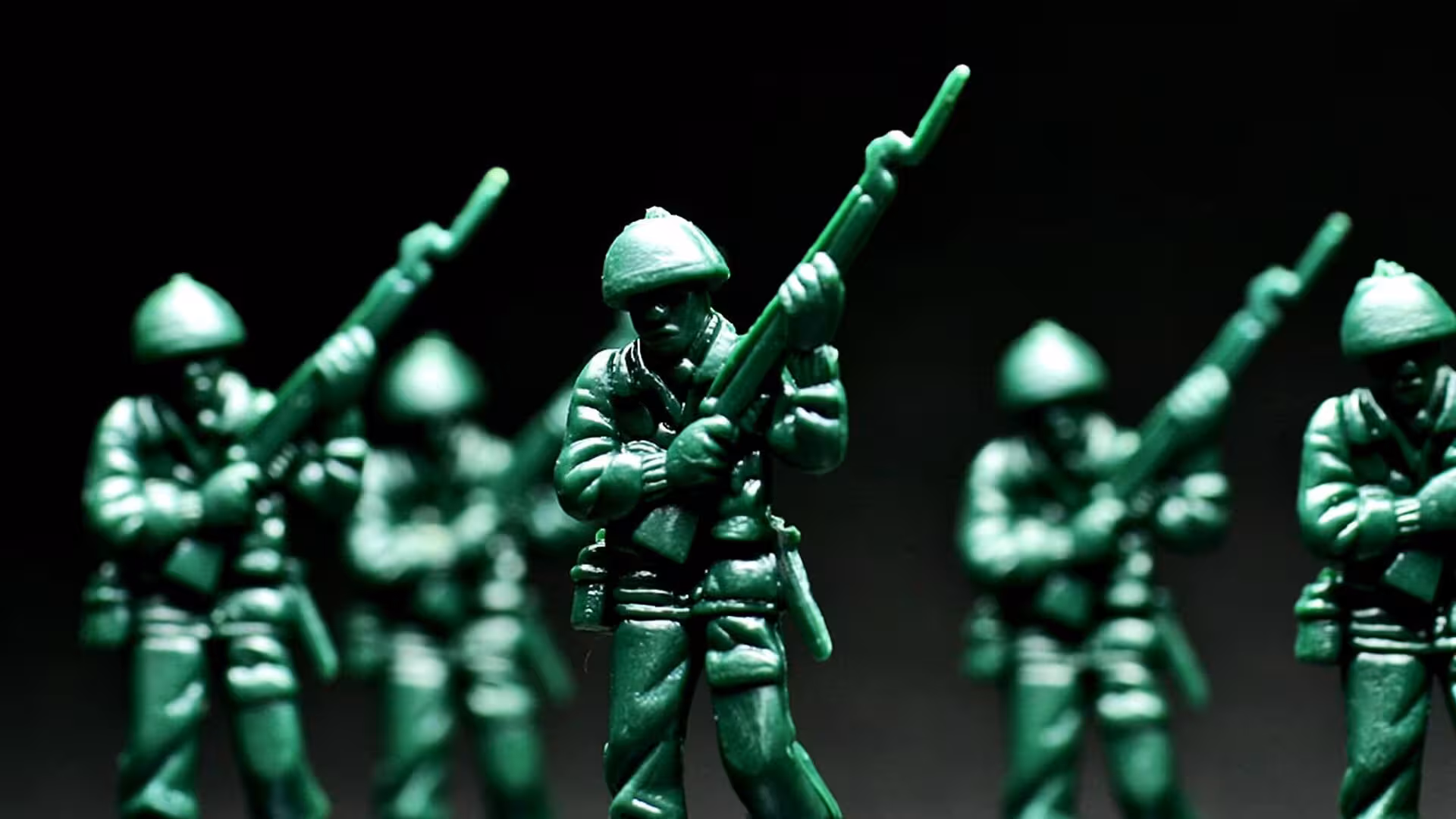 A row of green toy soldiers against a dark background.