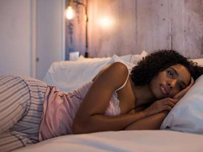 Beautiful black woman lying down on bed.