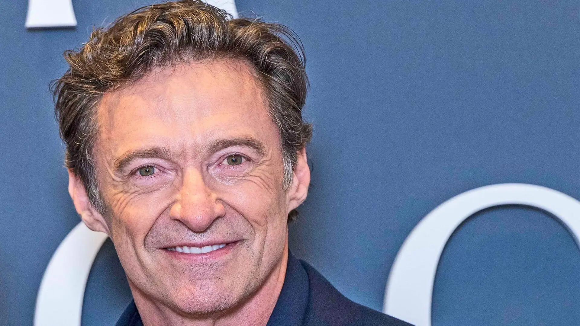 Hugh Jackman smiles at a red carpet event.