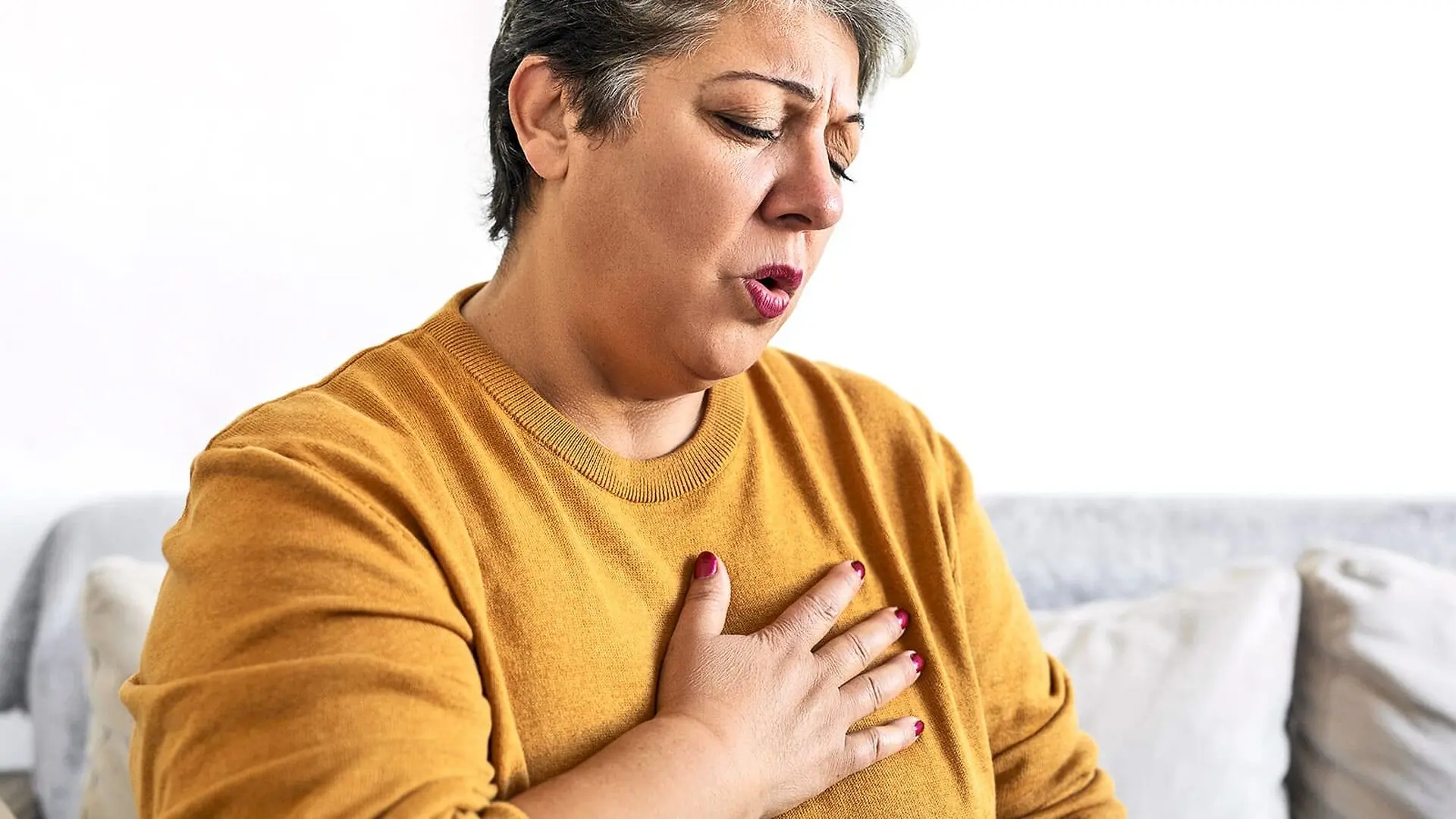 A woman holds her chest and grimaces.
