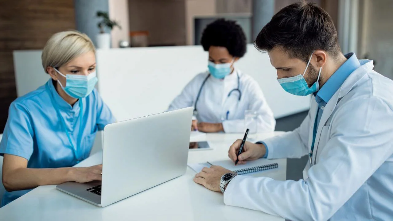Male doctor taking notes while working with colleagues at medical clinic