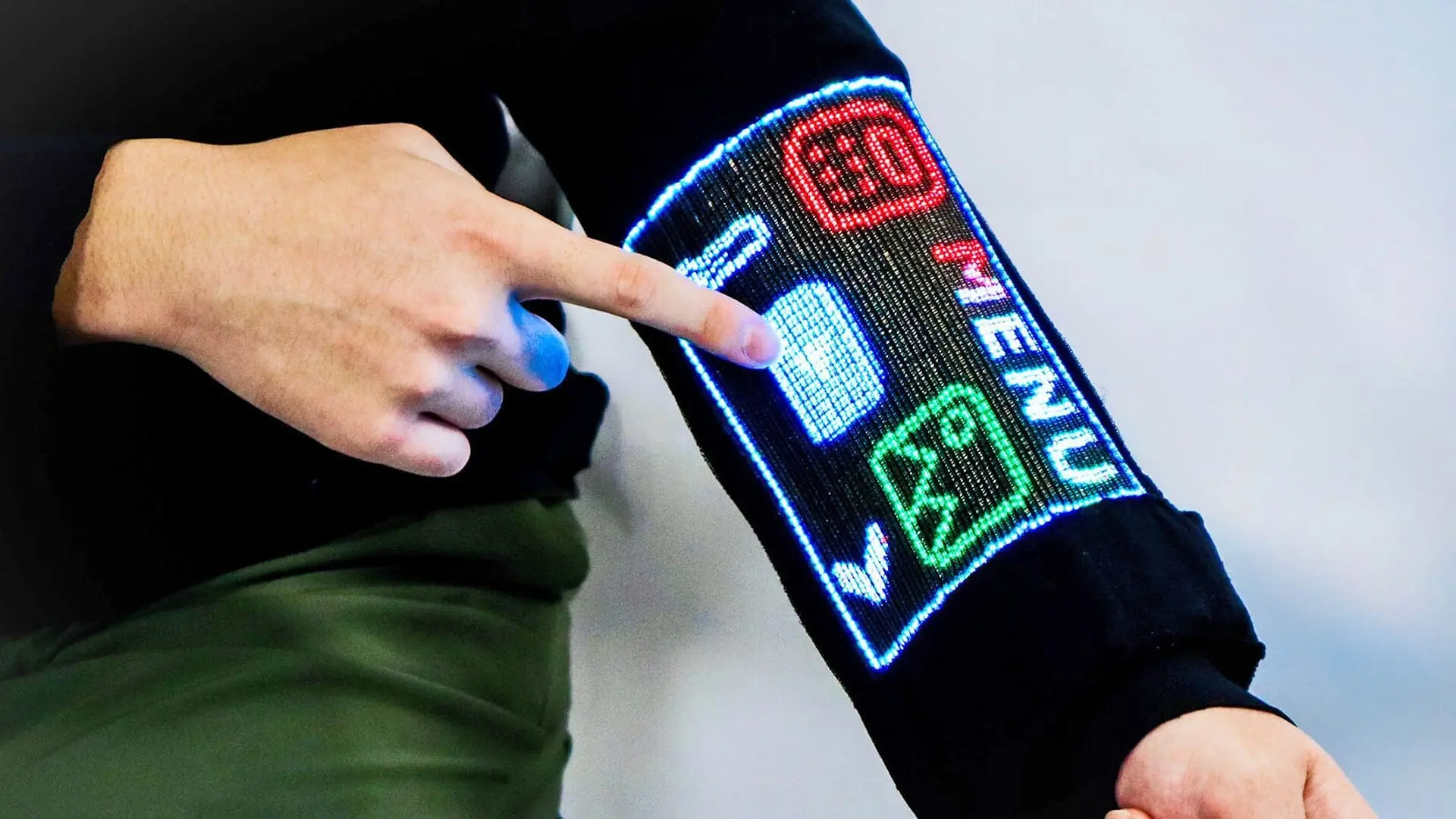 A person wearing the touchscreen clothing touches their arm, which is displaying a menu.