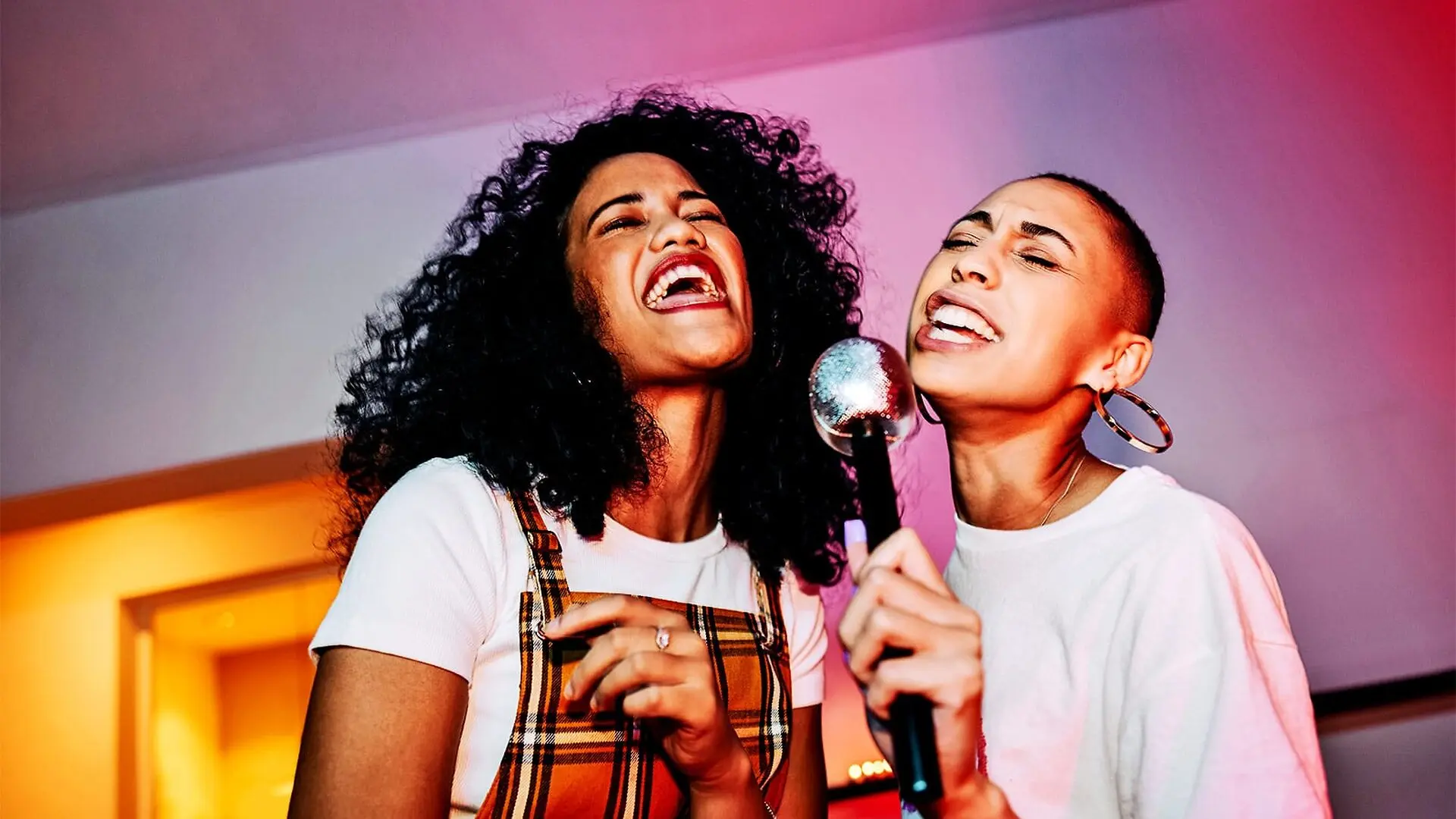 Two friends singing into a toy microphone.