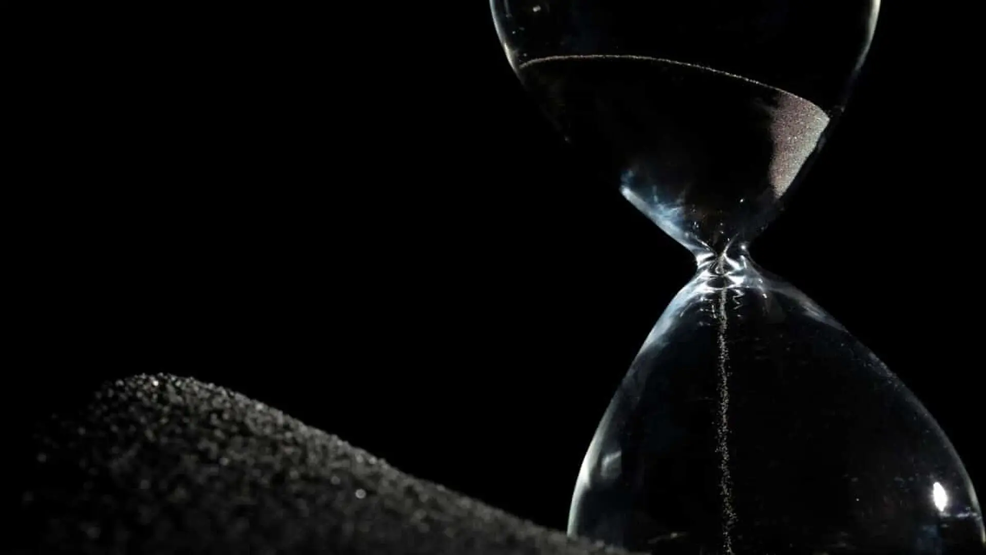 Hourglass Standing On Black Sand Scaled