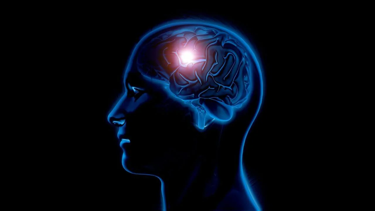 A profile silhouette of a human head in blue light, showing a detailed brain with a bright, glowing white and red focal point in the upper frontal region.