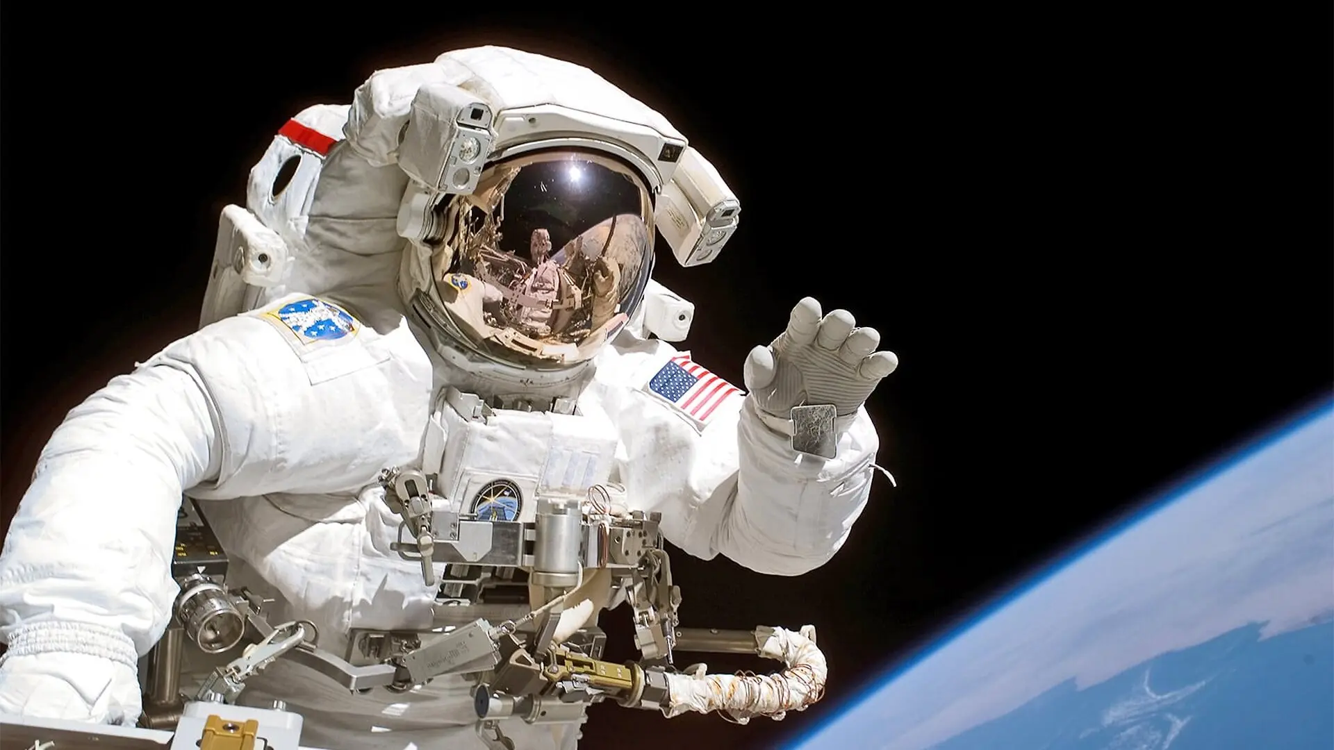An astronaut waves at the camera during a space walk.