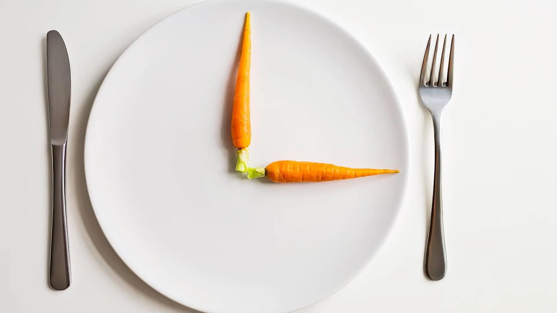 A plate with two carrots on it to make the plate look like a clock.