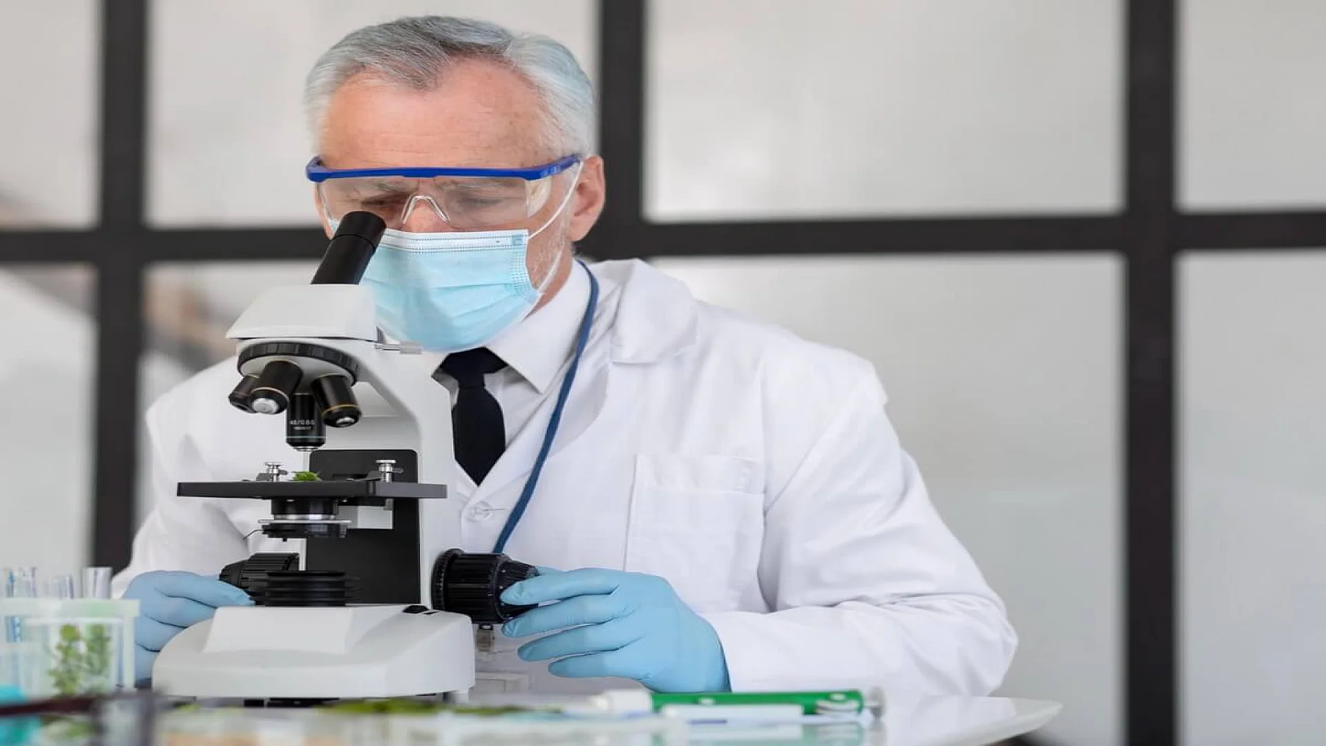 Free photo old scientist working with microscope.