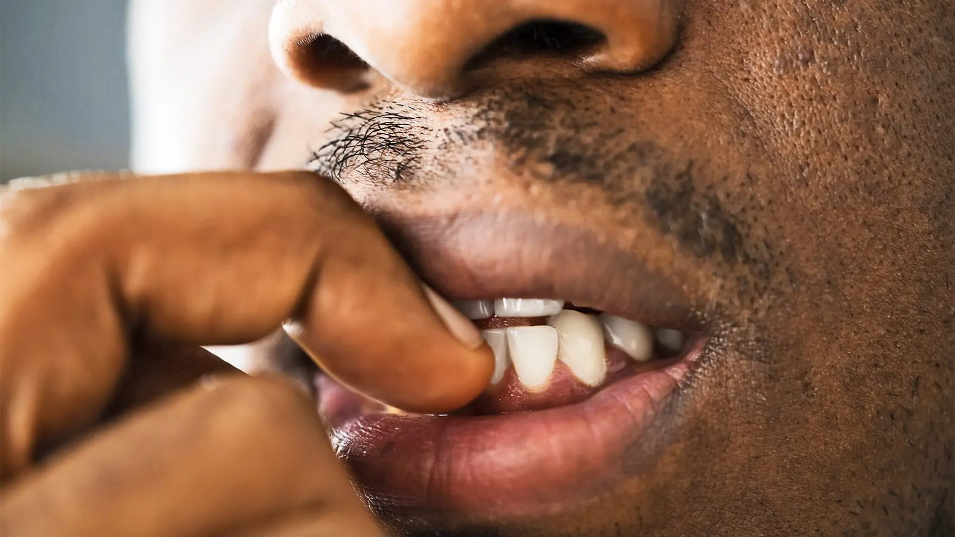 A man bites his nails anxiously.