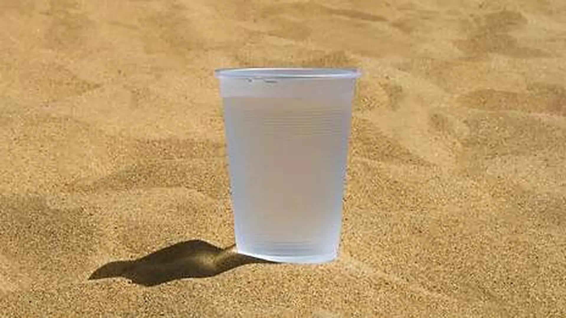 Plastic Glass With Cold Water On The Sand Scaled