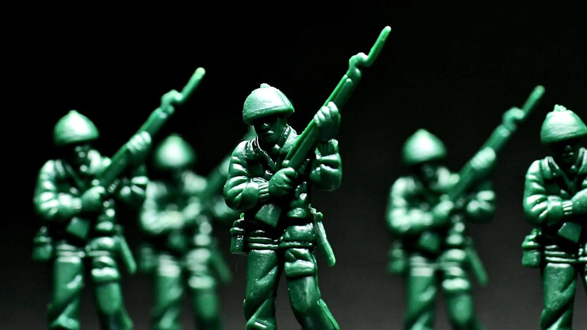 A row of green toy soldiers against a dark background.