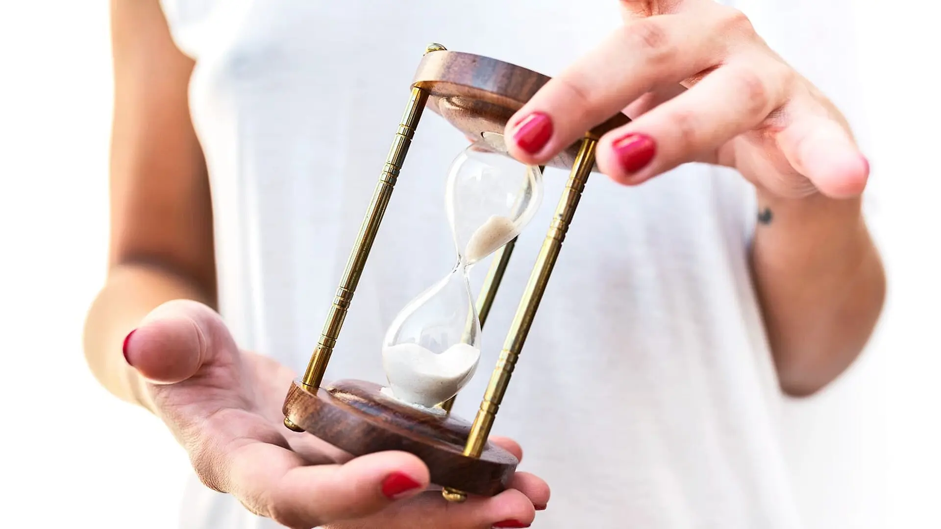 A woman holds a small hour glass.