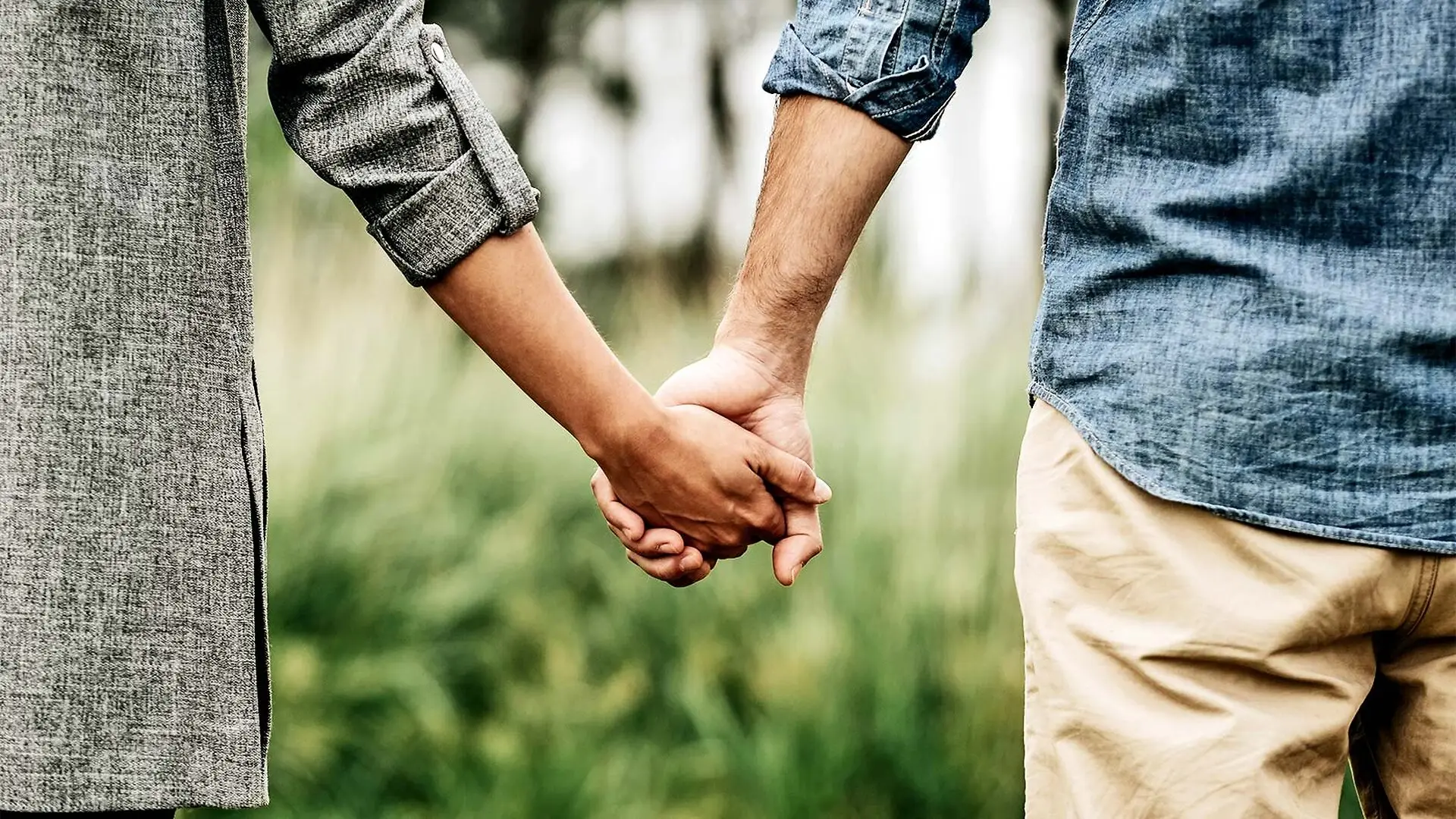 A couple holding hands while walking outside.