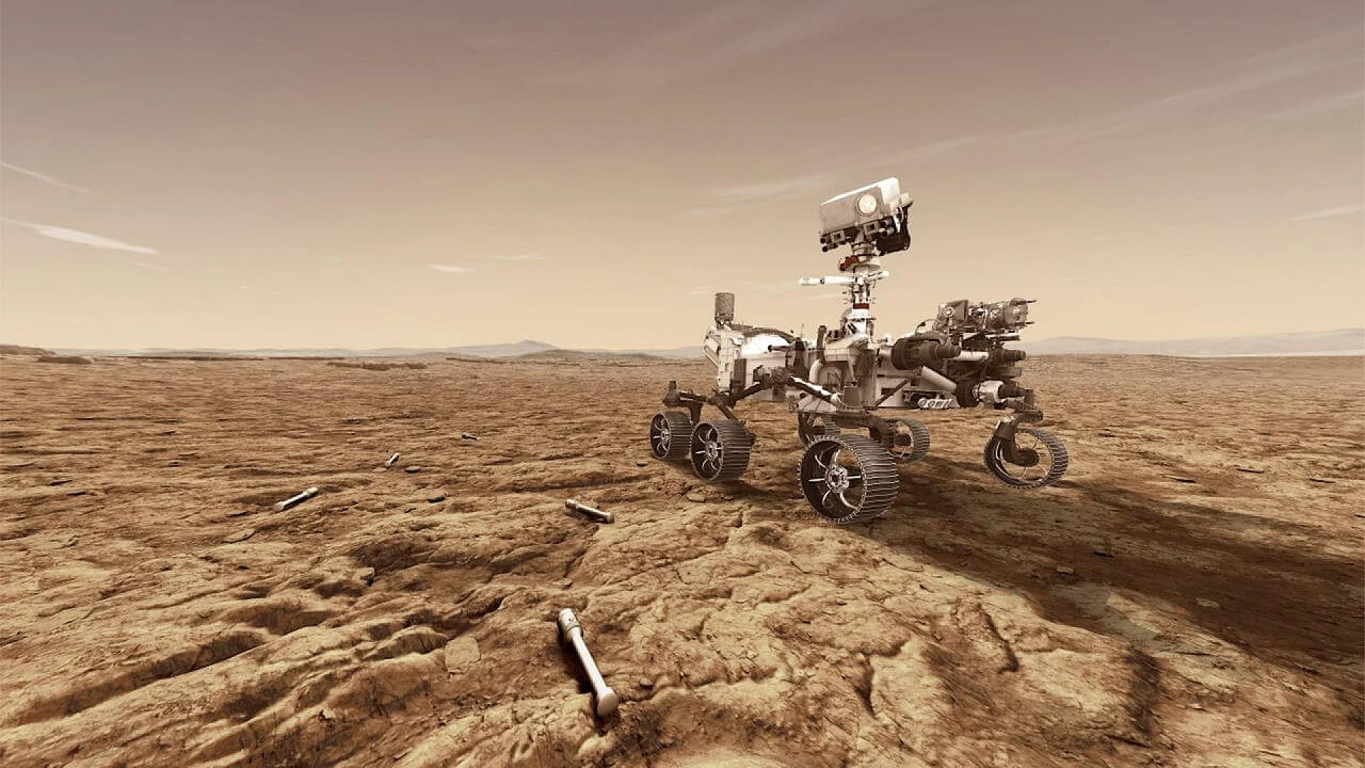 The Mars Perseverance rover stands on a rocky, rust-colored Martian plain with several silver sample tubes lying on the ground in the foreground under a hazy orange sky.
