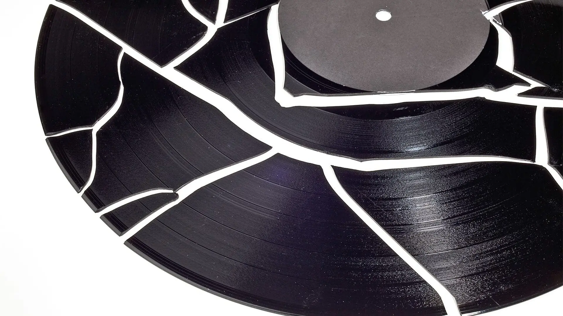A shattered vinyl record on a white surface.