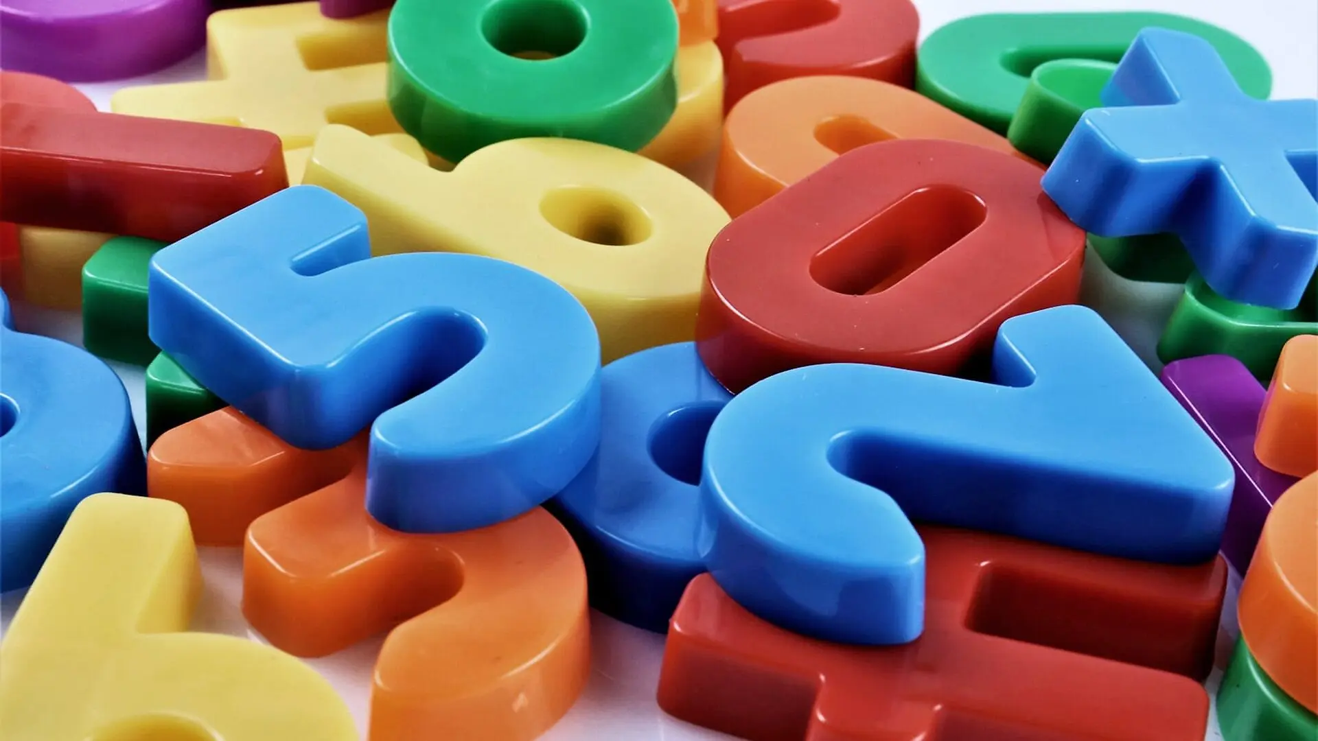 Colorful number and math symbol magnets in a large pile.