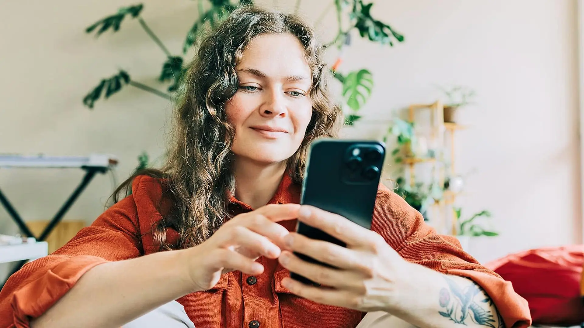 A woman smiles while scrolling on her phone.