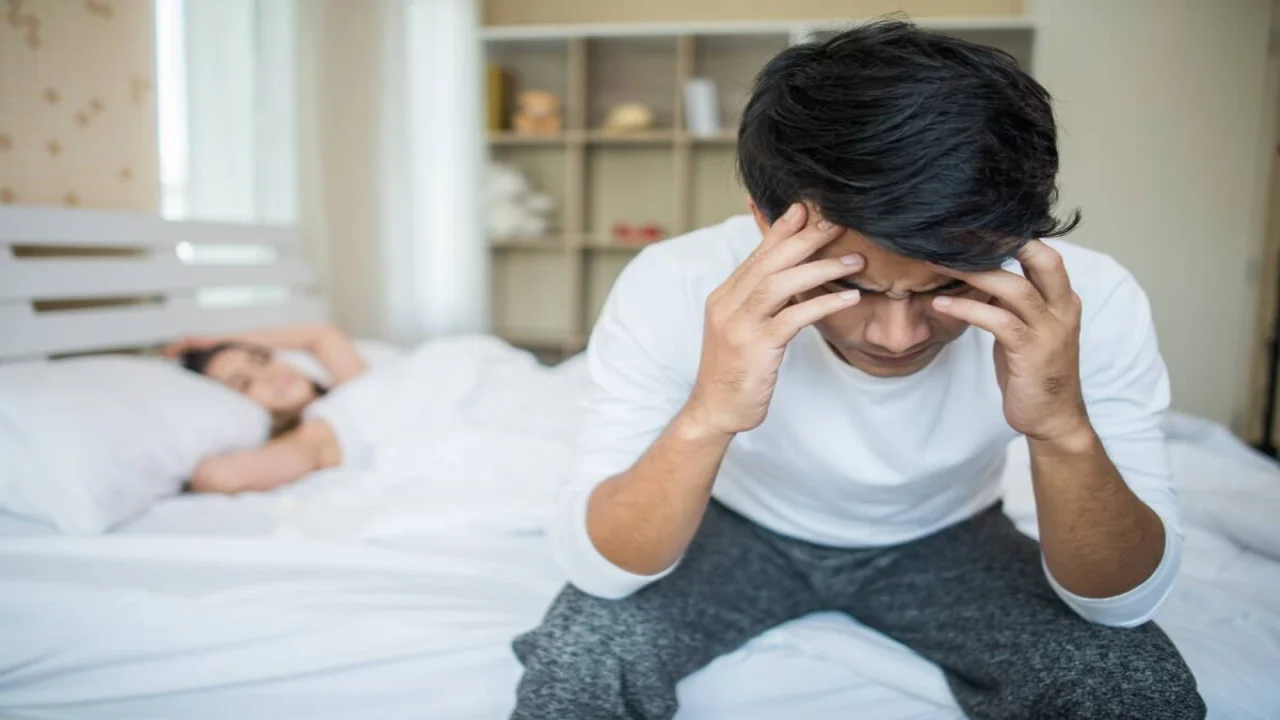 Upset man having problem sitting on the bed after arguing with his girlfriend.