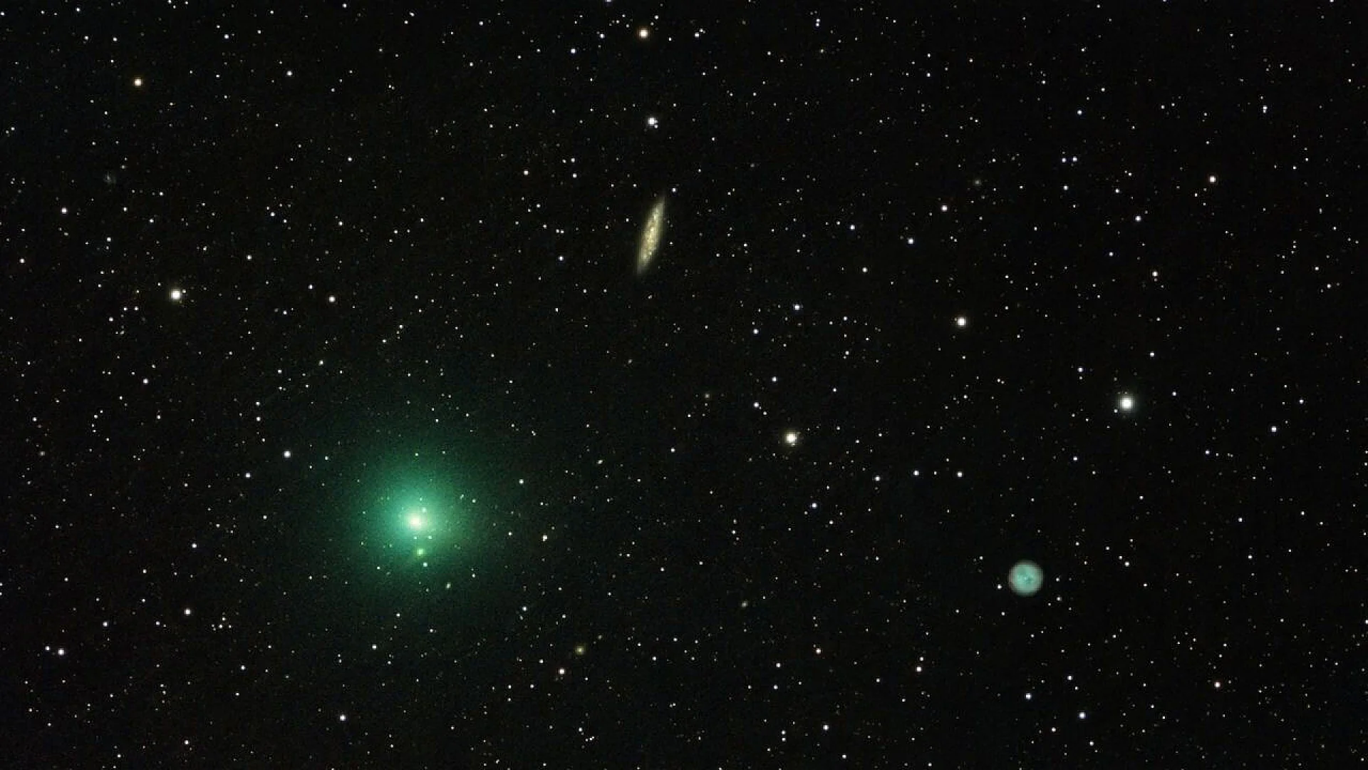 A wide-angle astrophotography shot showing the bright green coma of Comet 41P on the left, a slanted needle-like spiral galaxy in the upper center, and a faint blue-green planetary nebula on the lower right against a dense field of stars.