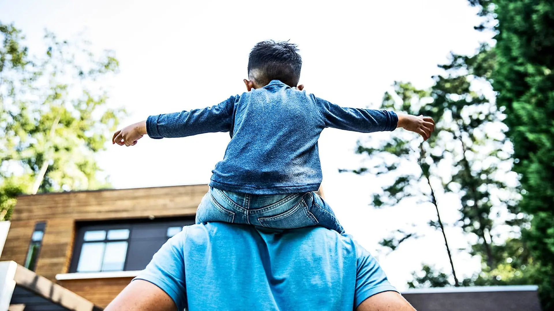 A young child with arms outstretched sits on a parent