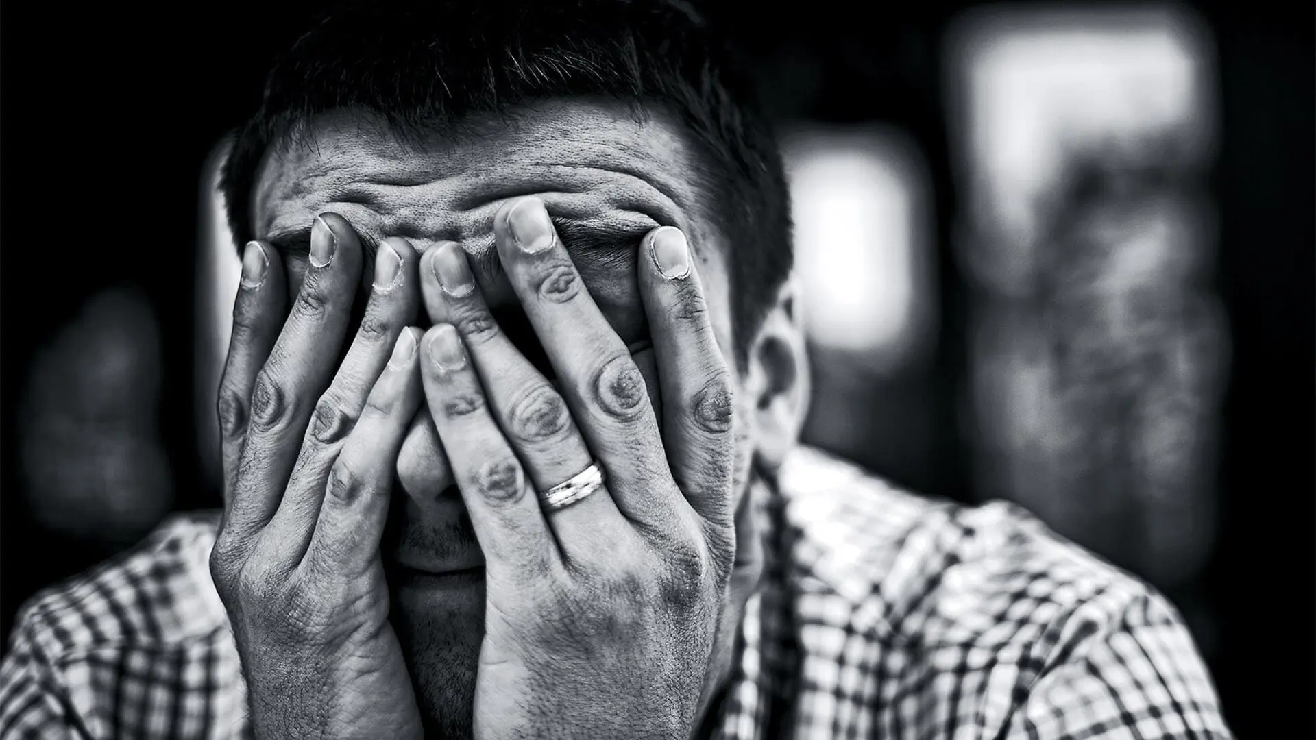 A man covers his face with both hands.