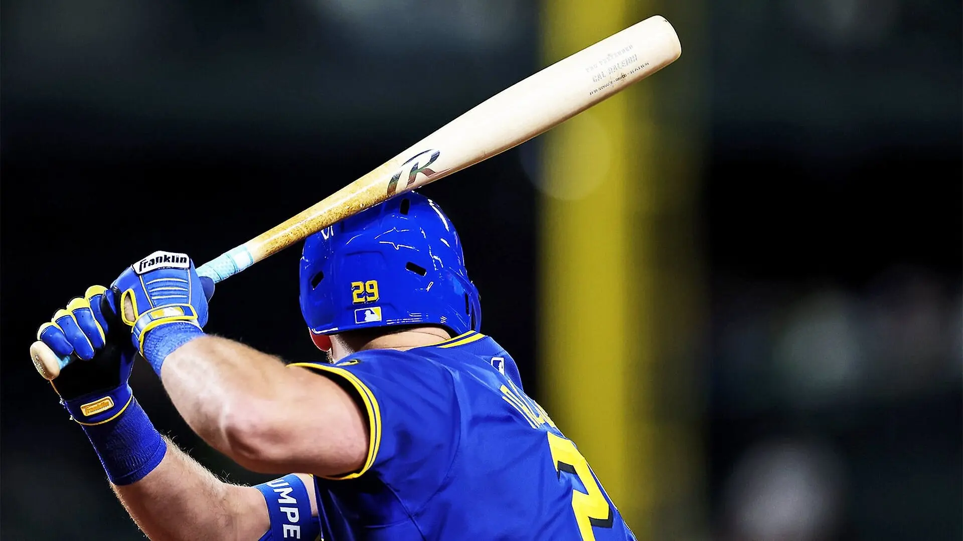 A baseball player holds up a torpedo bat while waiting to swing at an oncoming pitch.