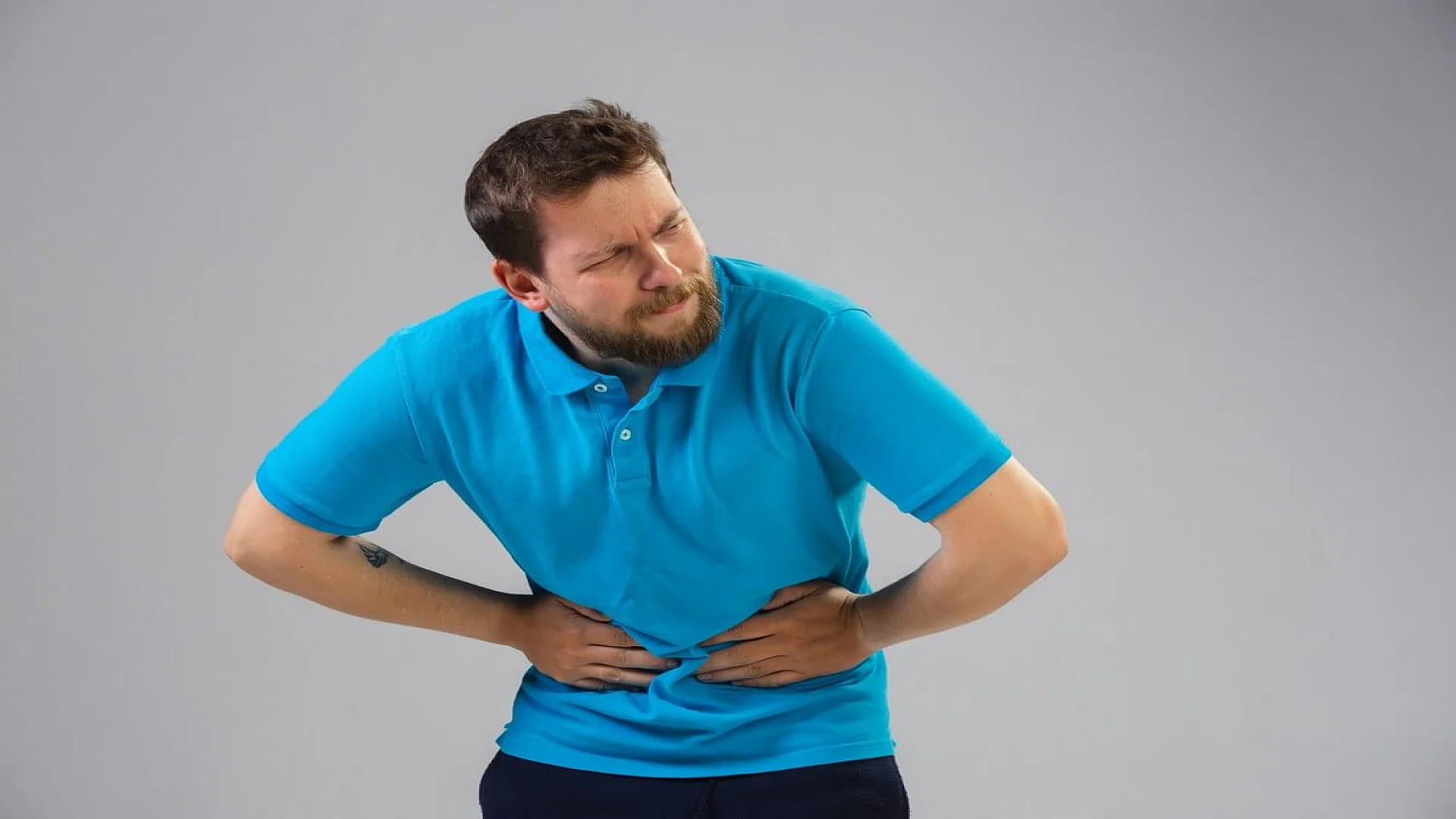 Free photo young caucasian man suffers from abdominal pain.
