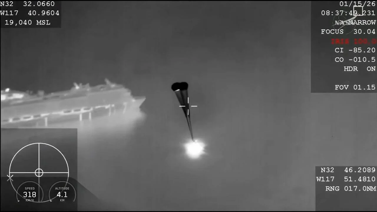 A grainy, black-and-white thermal infrared camera view of a SpaceX Crew Dragon capsule descending under parachutes at night, with a bright heat signature visible at the base. On-screen telemetry displays coordinates, altitude, and a date of 01/15/26.