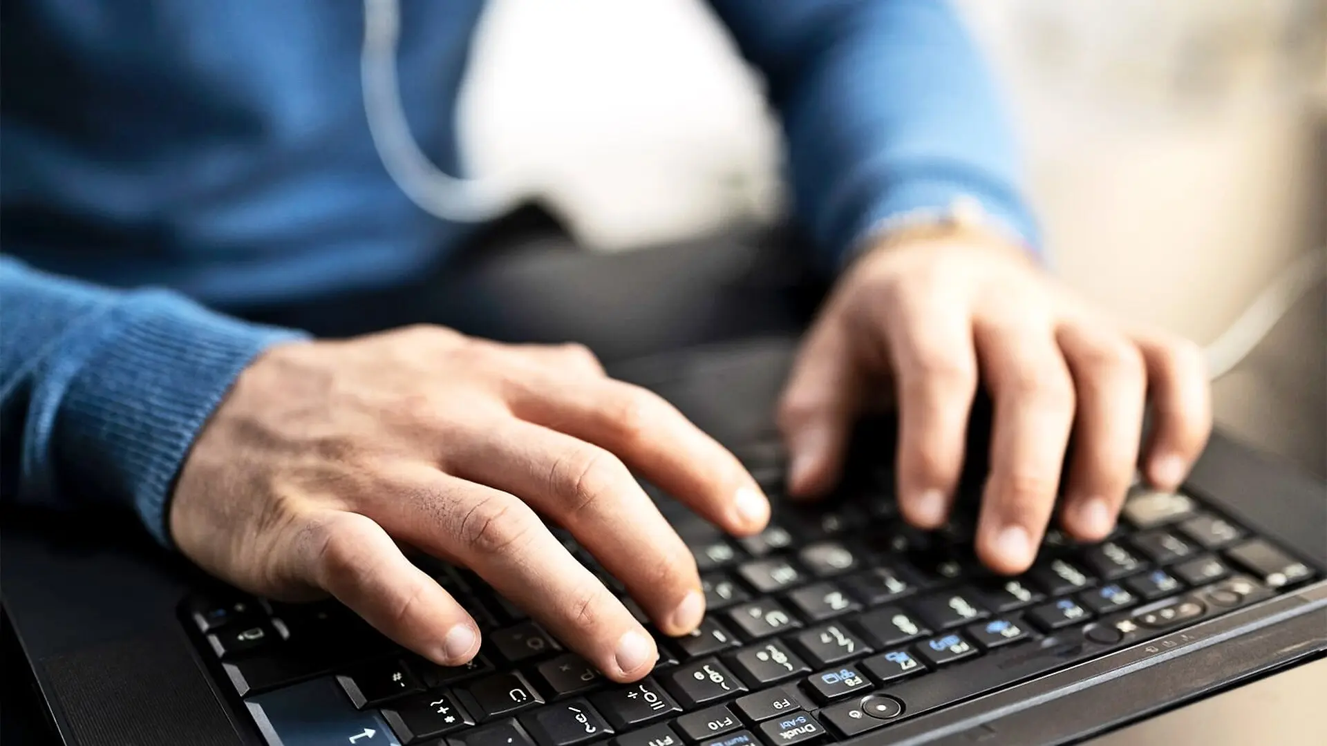 A man types on a computer keyboard.
