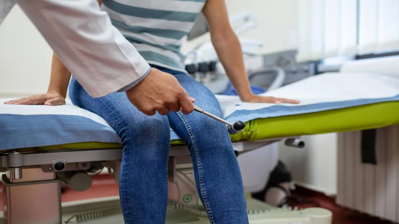 Free photo doctor neurologist knocking on knee of patient with hammer in clinic closeup diagnosis of neurological pathology of knee reflex concept.