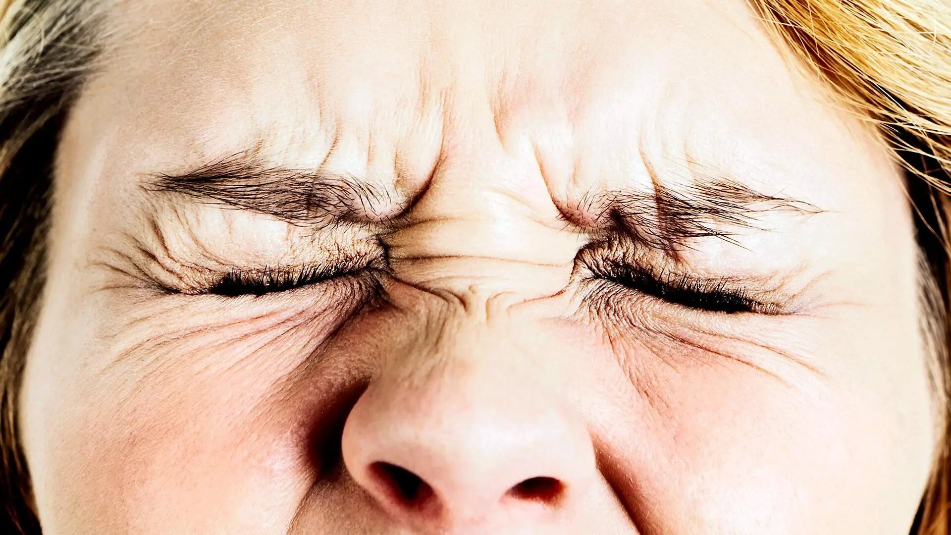 A close-up of a woman grimacing in pain.