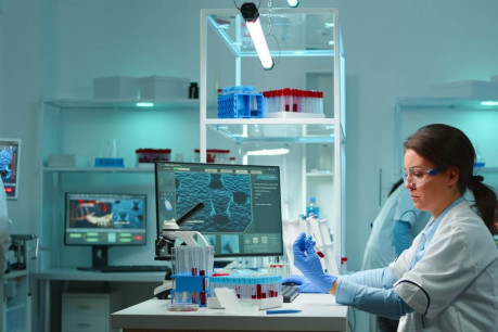 Medical lab worker analyzing blood serum conducting virus test in modern equipped lab late at night. team of specialists examining vaccine evolution using high tech for treatment against covid19.