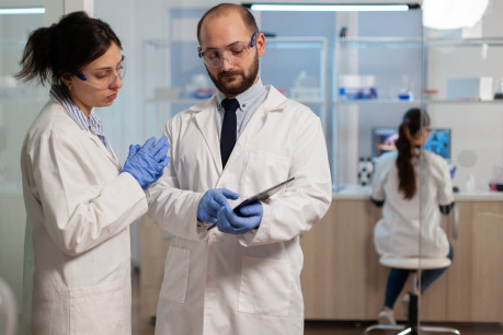 Chemist nurse explainig to doctor vaccine development in modern laboratory.