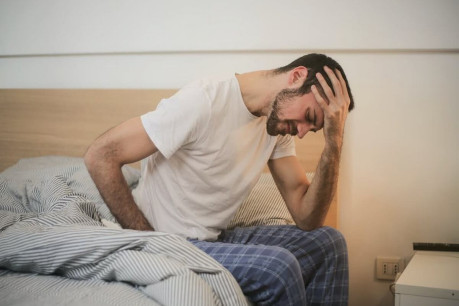 Young man in sleepwear suffering from headache in morning.