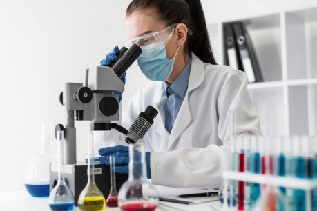 Free photo medium shot woman looking through microscope.