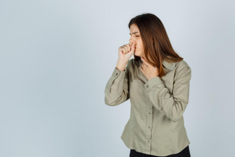 Young lady in shirt, skirt suffering from cough and looking sick, front view.